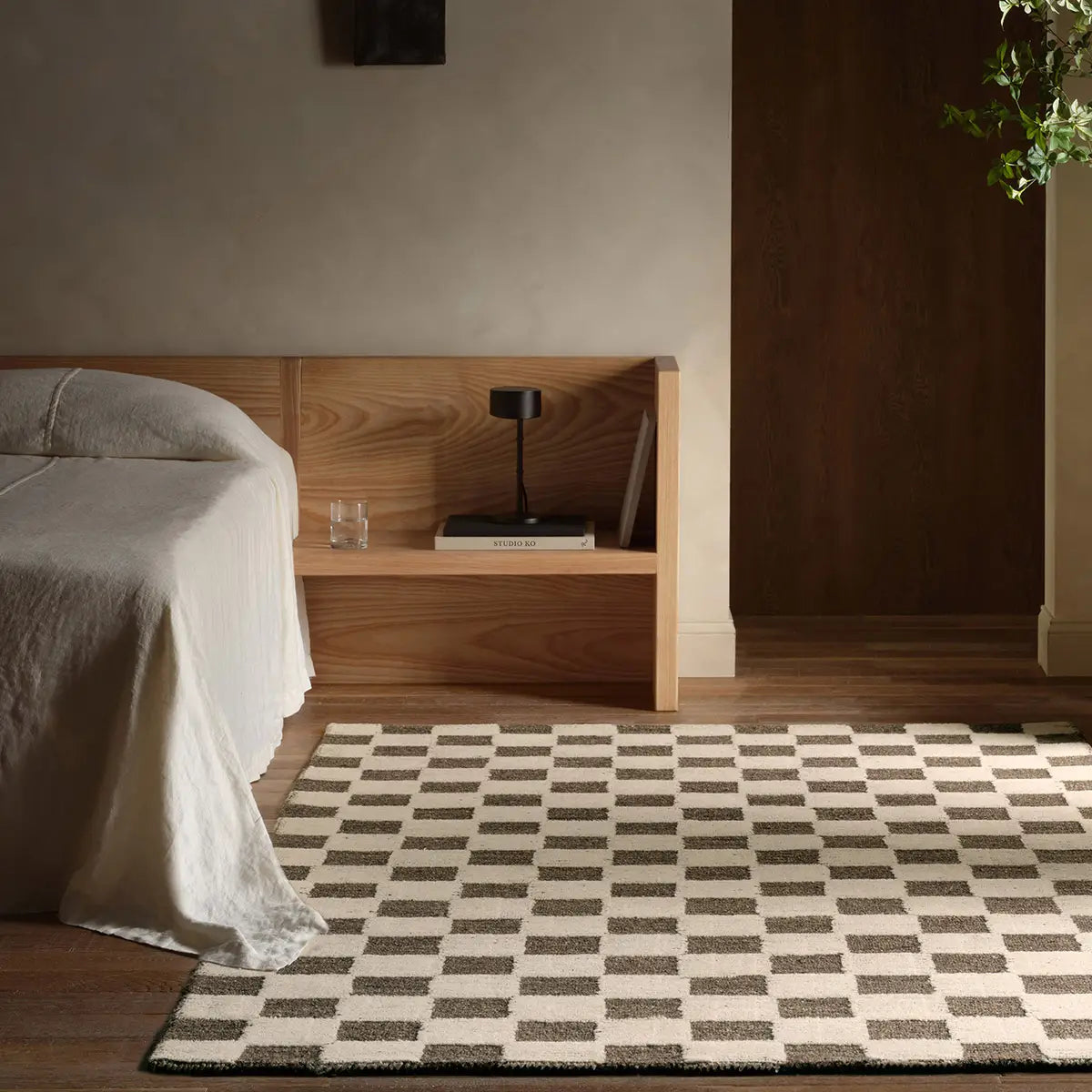 Bedroom with wooden headboard, checkered rug, and minimal decor.