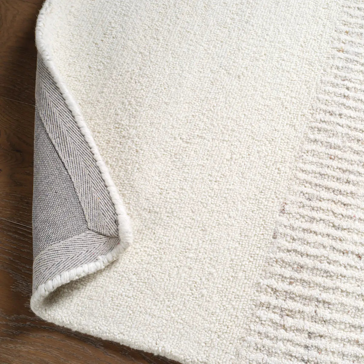 Close-up of a textured rug corner on a wooden floor