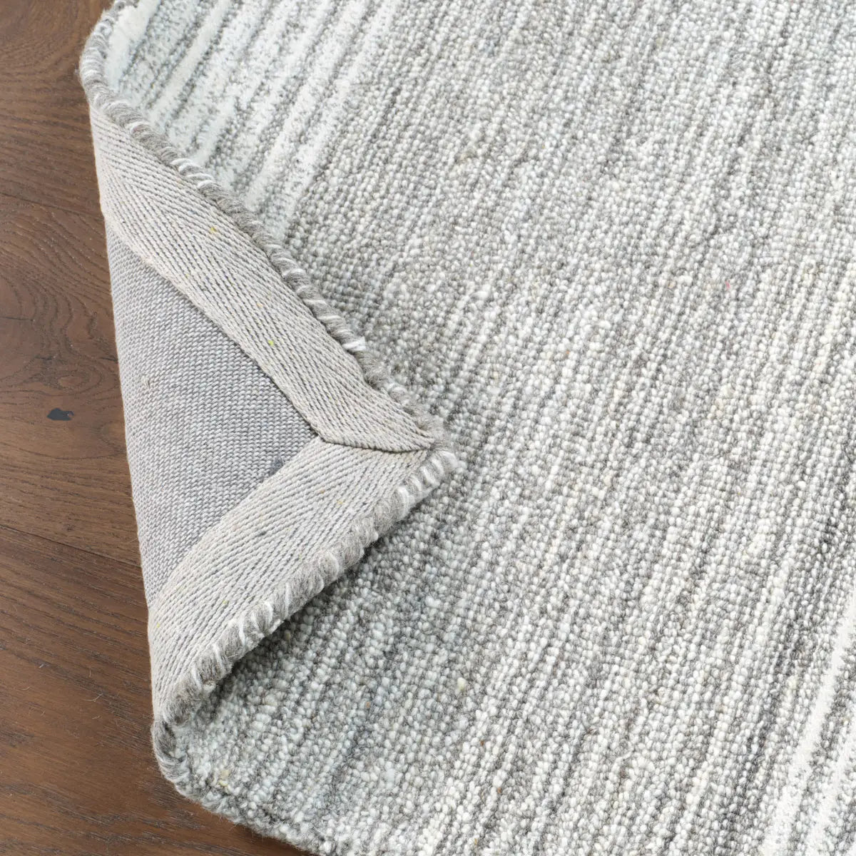 Close-up of a textured gray rug on a wooden floor