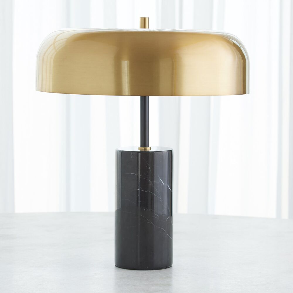 Table lamp with gold shade and black base on a white surface