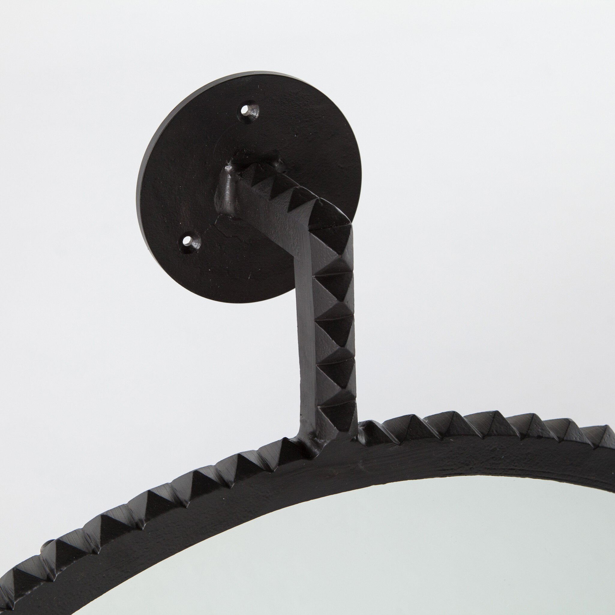 Black metal wall mirror with geometric design on a white background