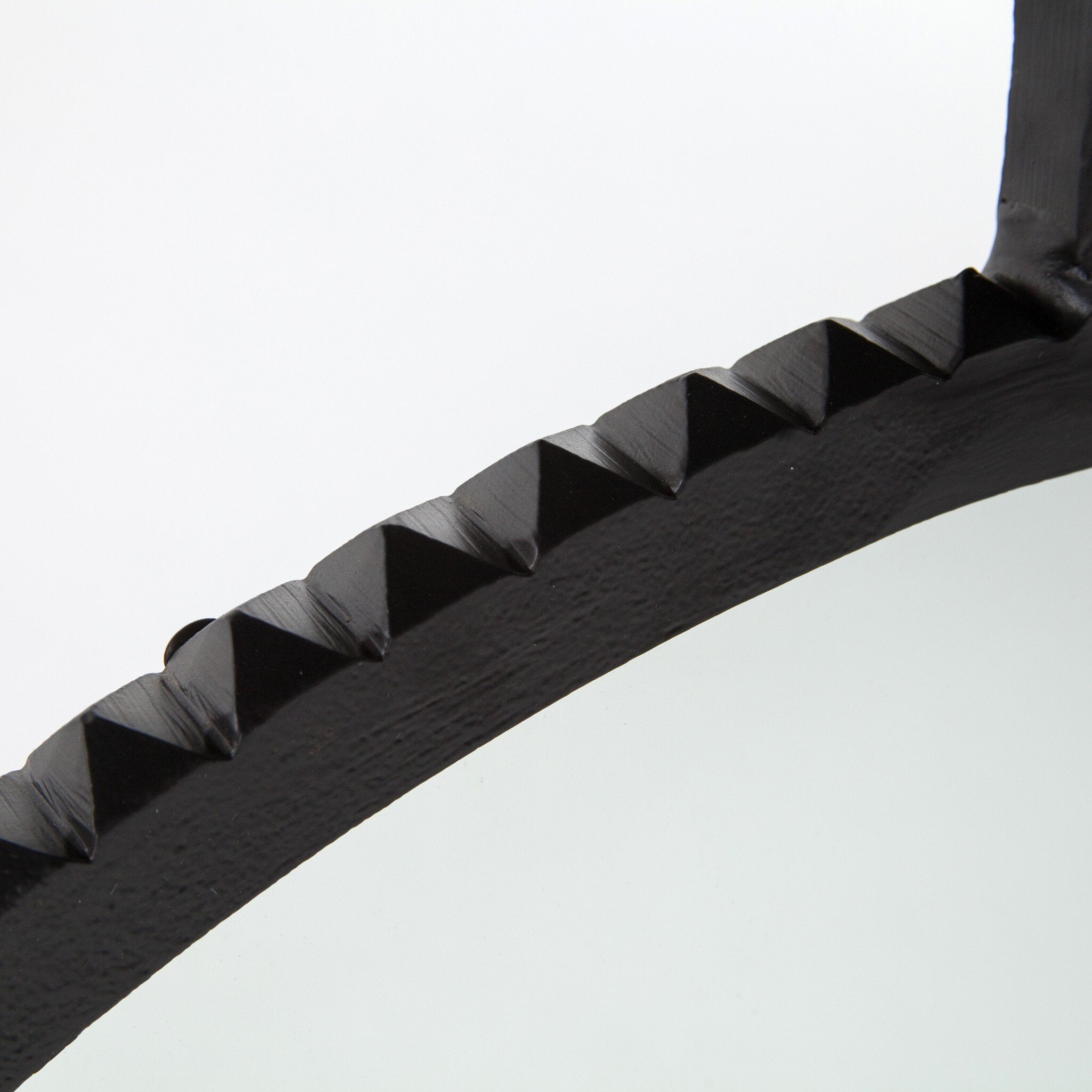 Close-up of a black metal mirror with carved pattern on a white background