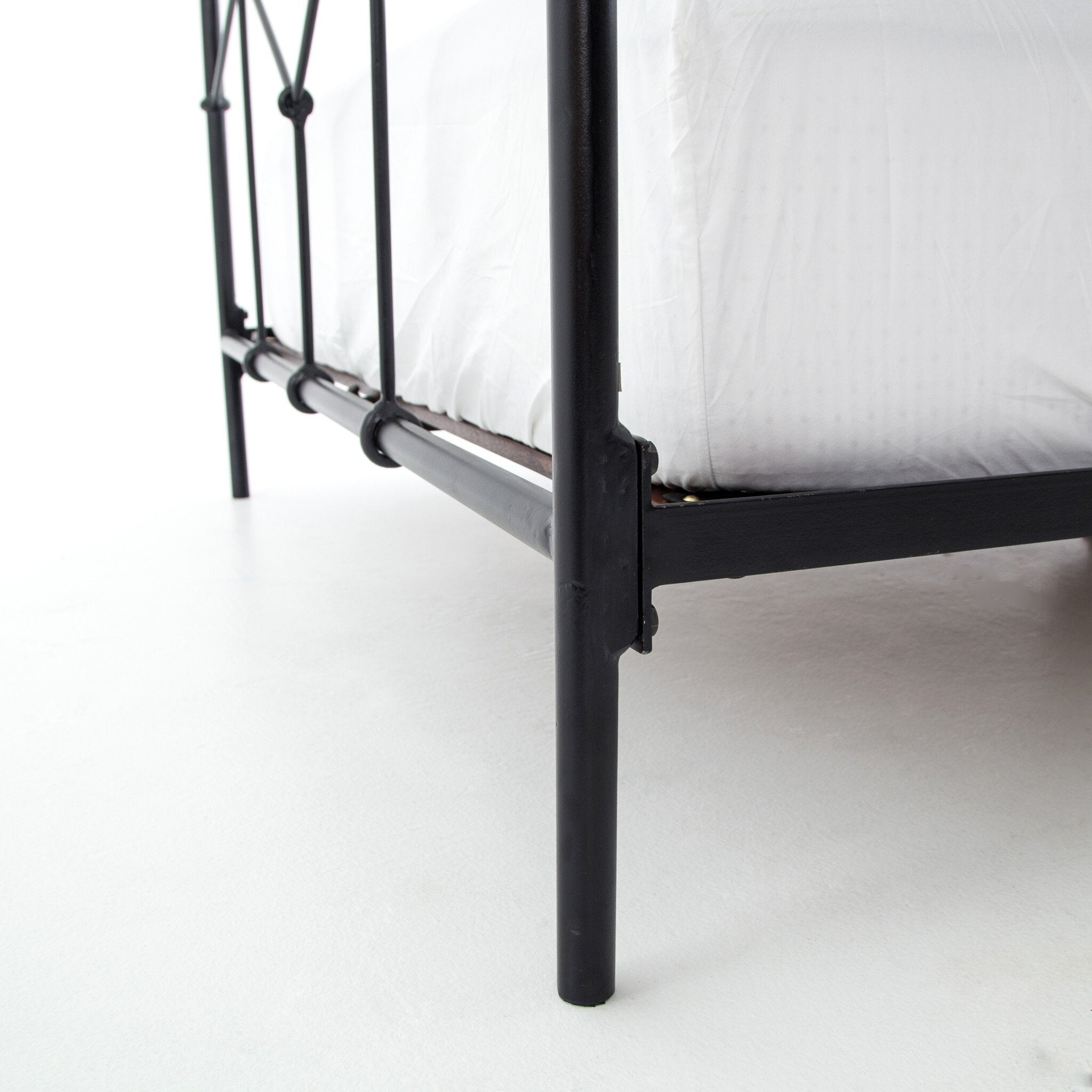 Black metal bed frame with white mattress on a white background
