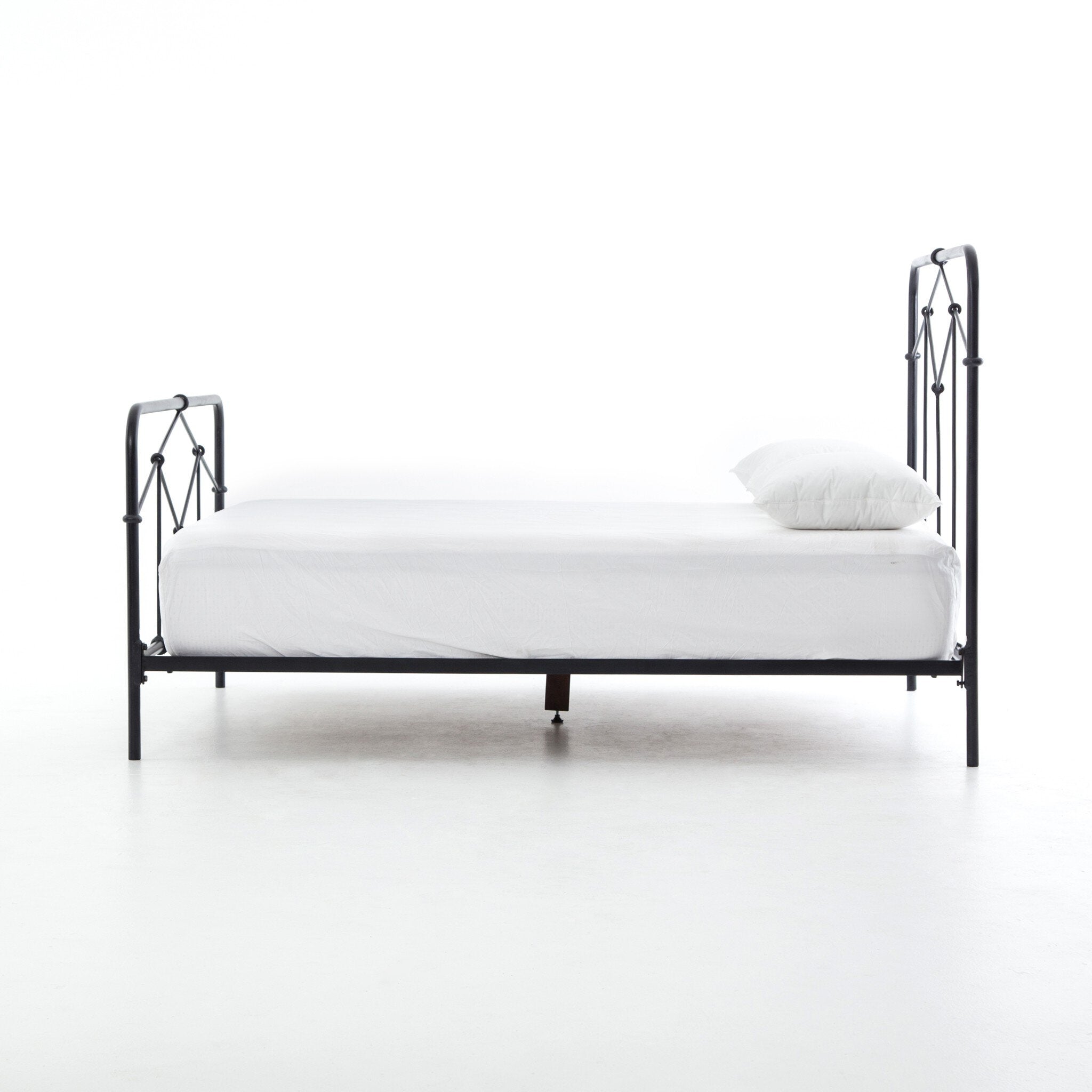 Black metal bed frame with white bedding on a white background