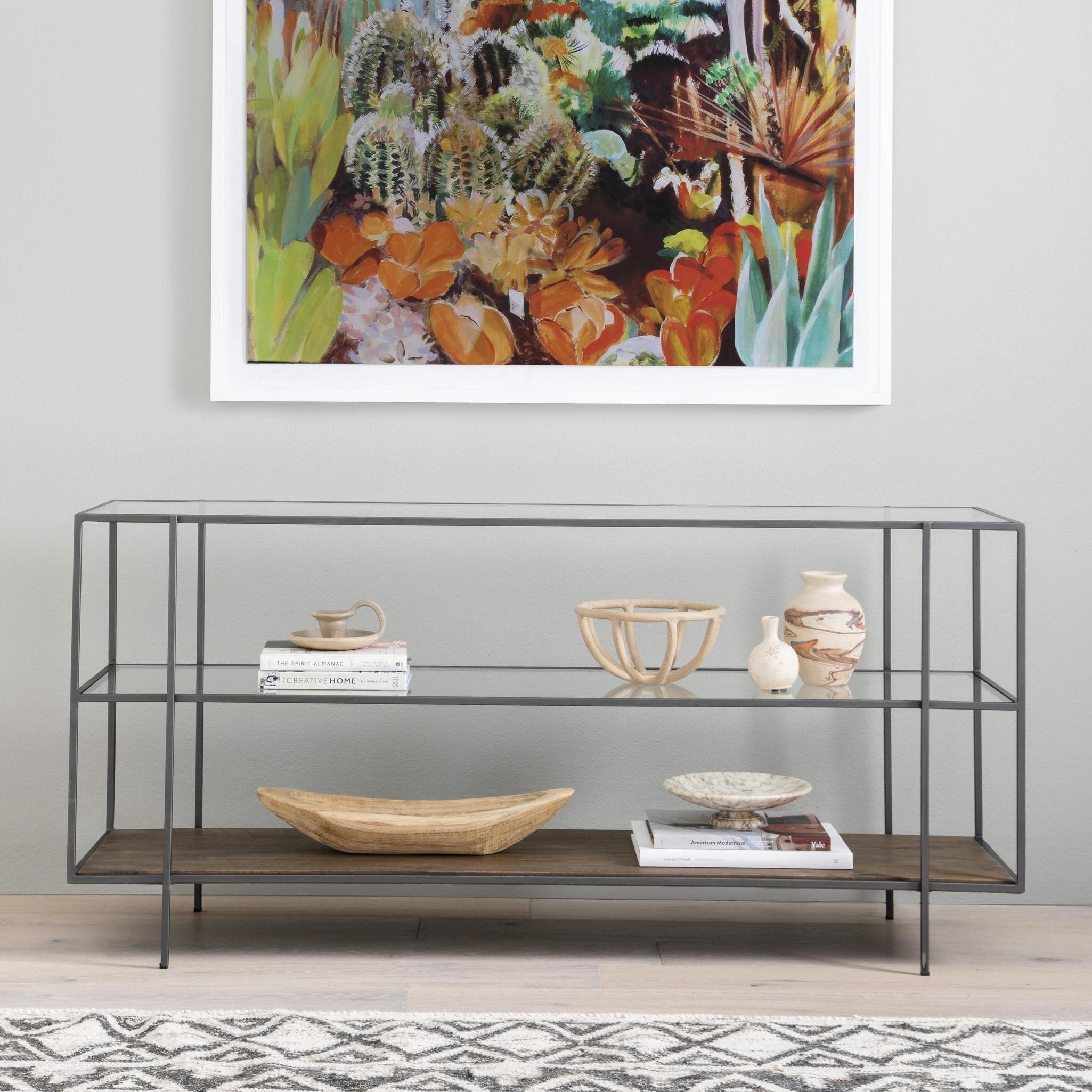 Console table with decorative items against a wall with a colorful abstract painting.