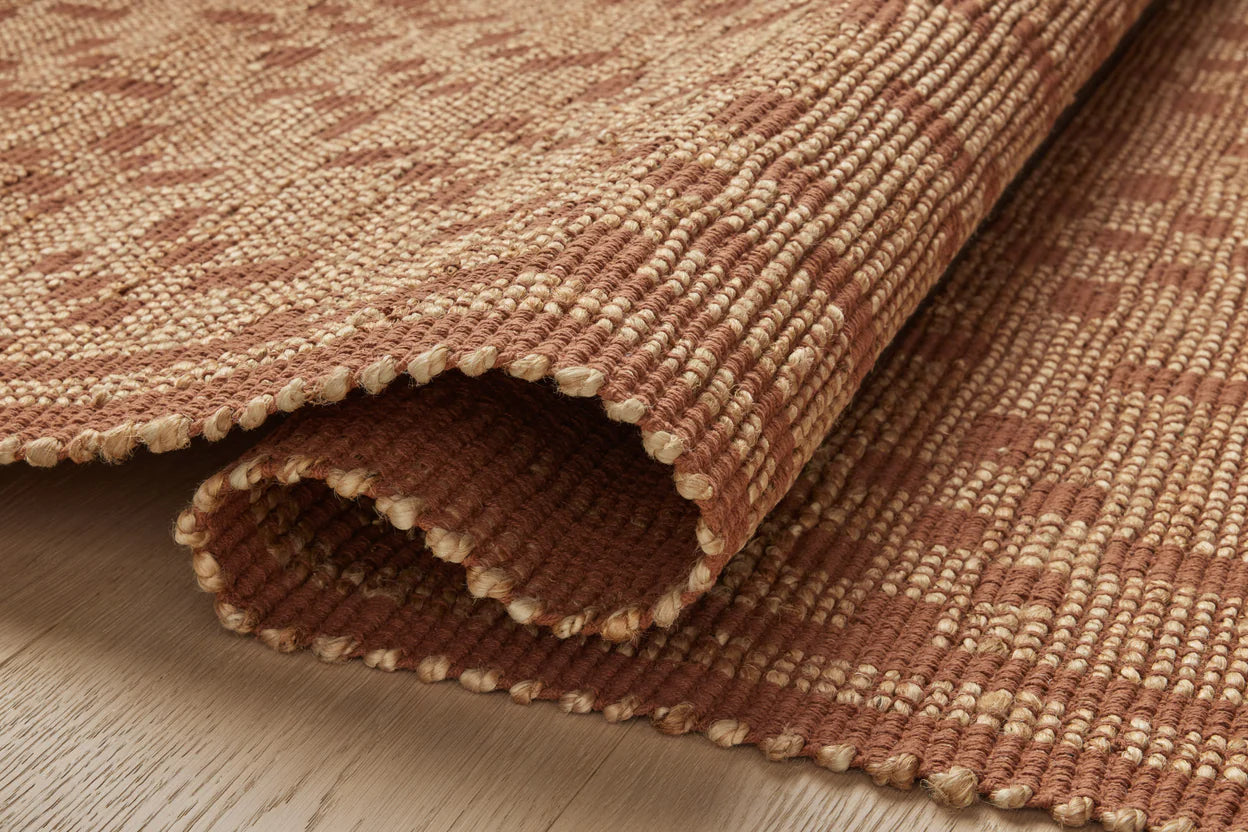 Close-up of a textured brown and beige rug on a wooden floor.