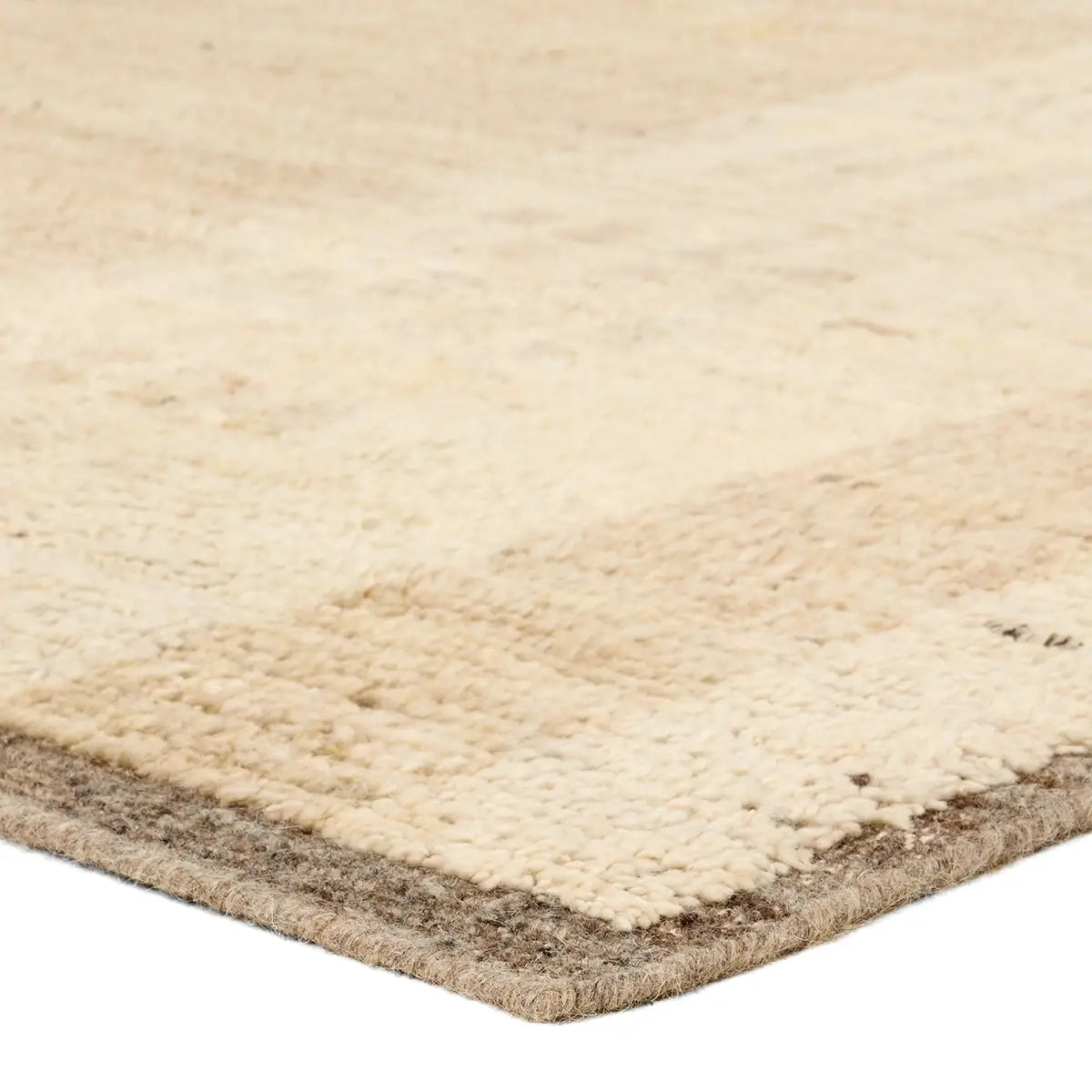 Close-up of a textured beige rug corner on a white background