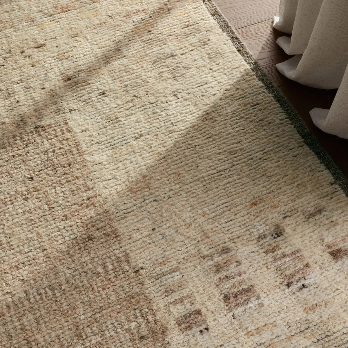 Close-up of a textured beige rug with a slight pattern on a wooden floor.