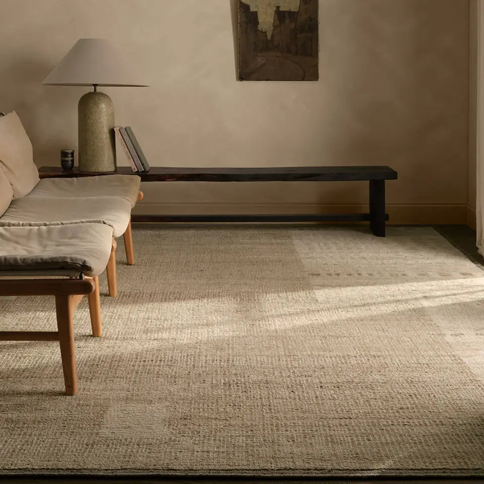 Living room with a textured rug, wooden bench, and lamp.