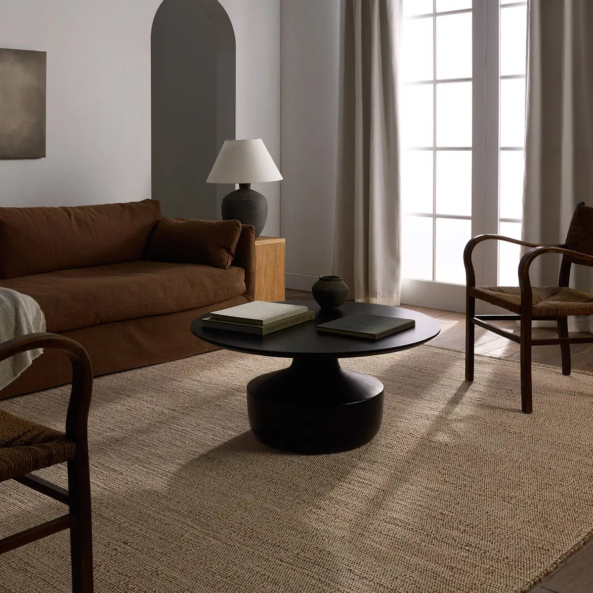 Living room with brown sofa, black coffee table, and wooden chairs.