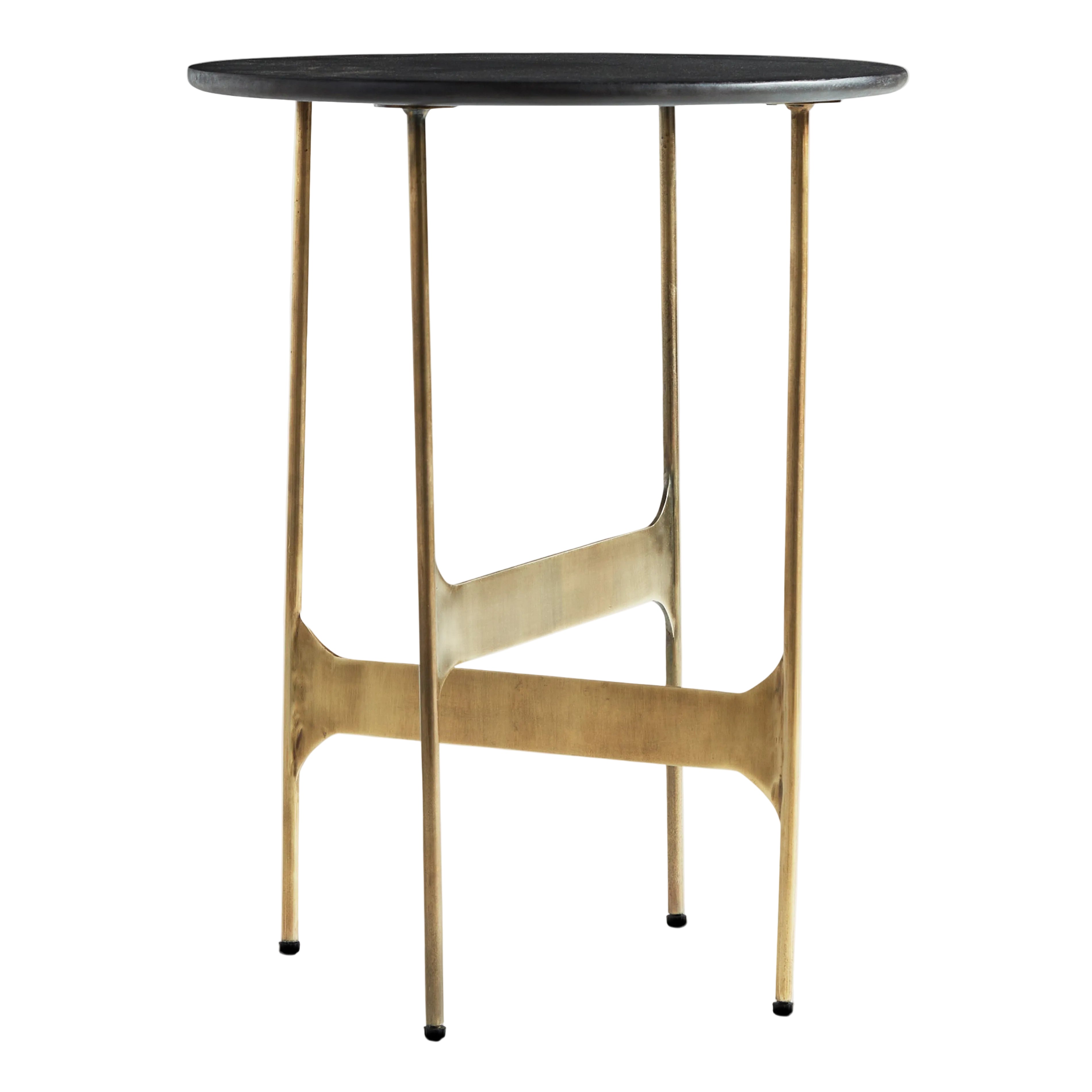 A modern round side table with a black stone top and a brushed brass metal frame with four legs and a central support bar, shown on a light gray background.