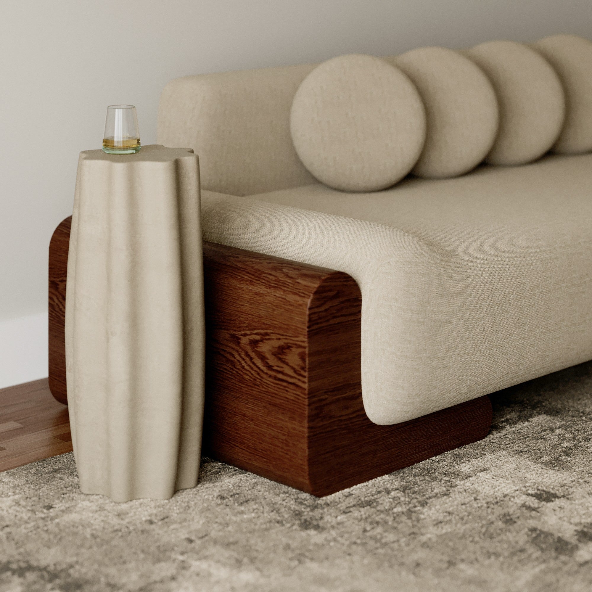 Beige sofa with wooden legs next to a cylindrical side table on a textured floor.