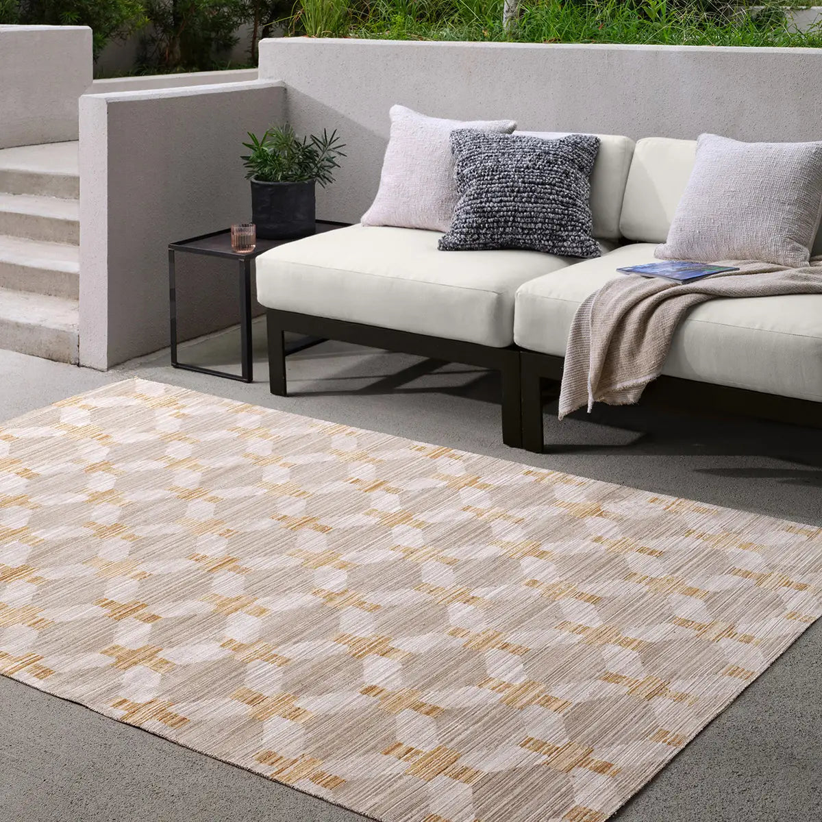 Outdoor seating area with a patterned rug, sofa, and small table.