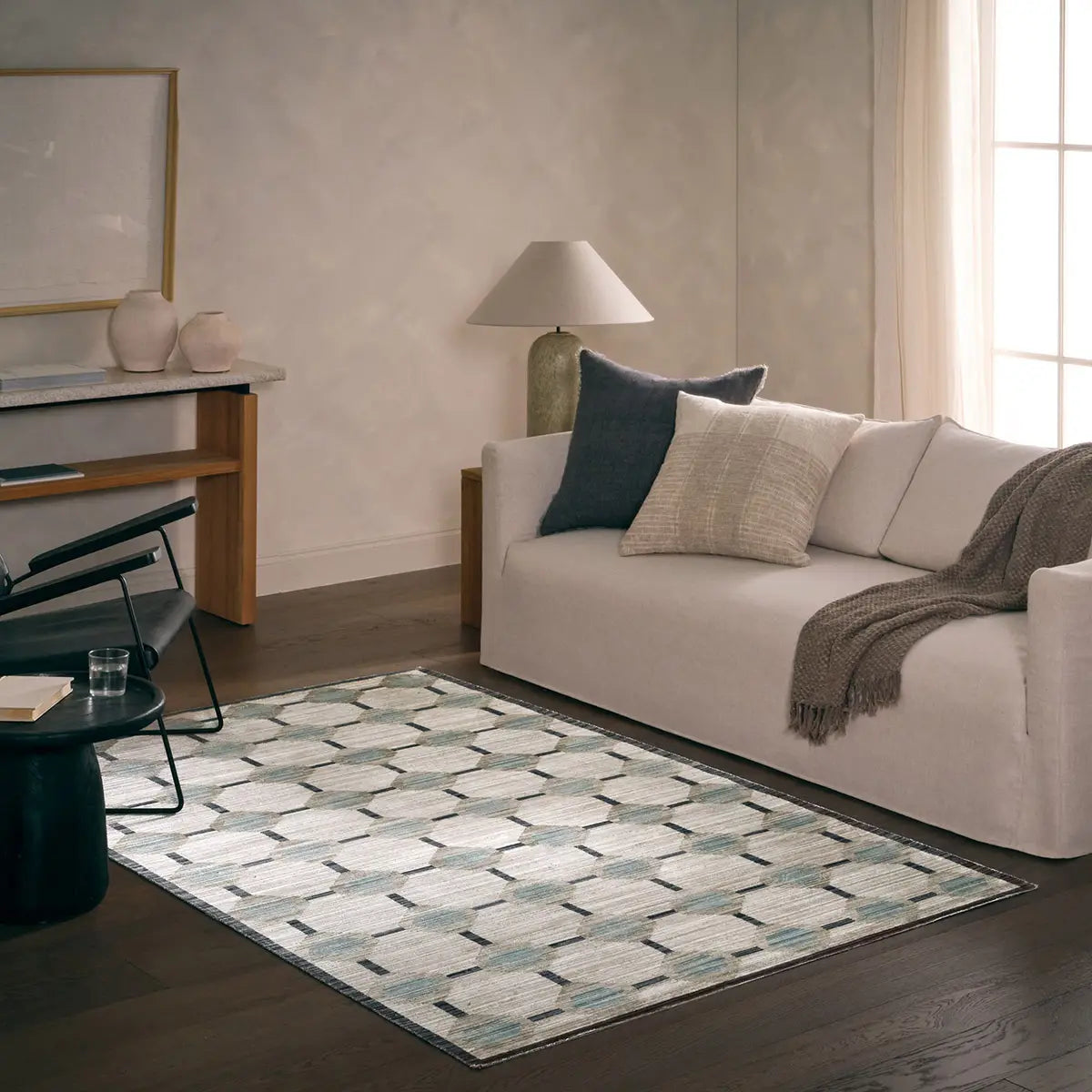 Living room with a patterned rug, sofa, and lamp.