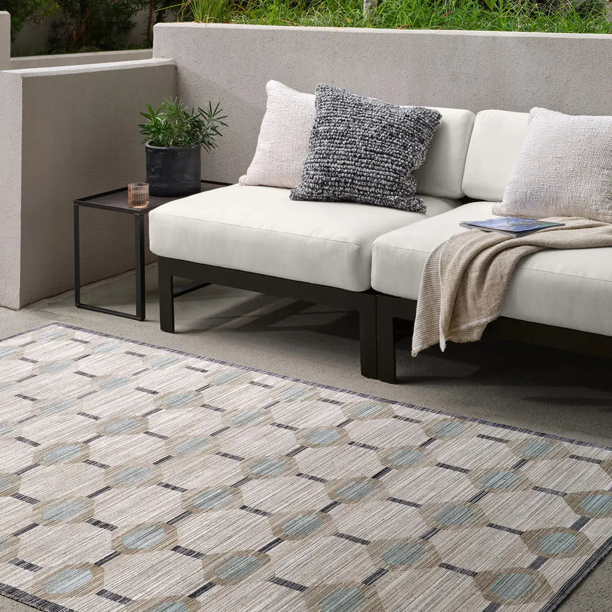 Outdoor patio with a sectional sofa, side table, and patterned rug.