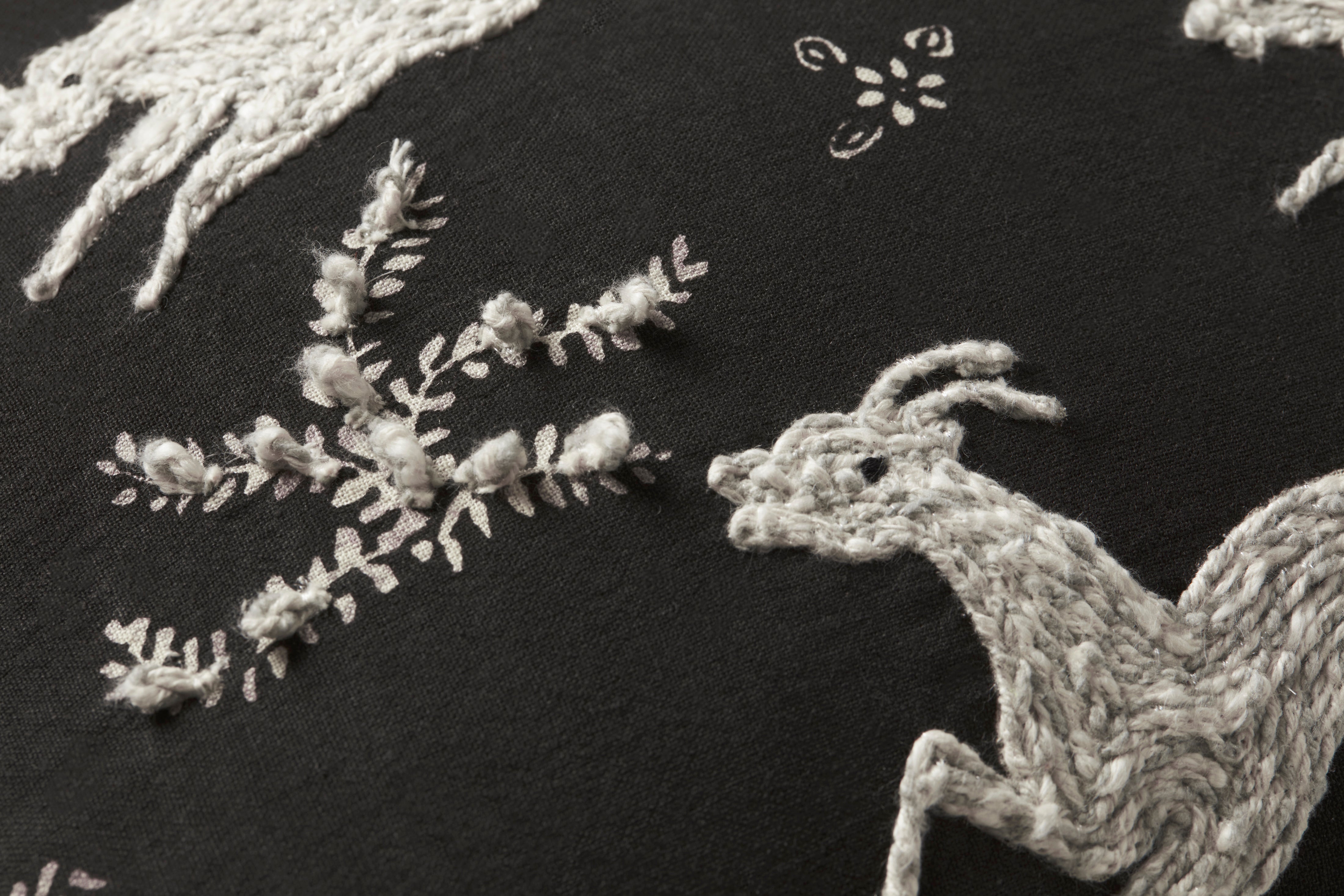 Embroidered design of a deer and floral elements on black fabric