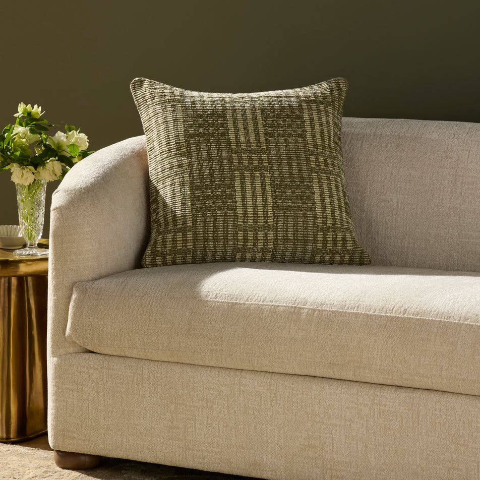 Beige sofa with a green patterned pillow in a living room setting.