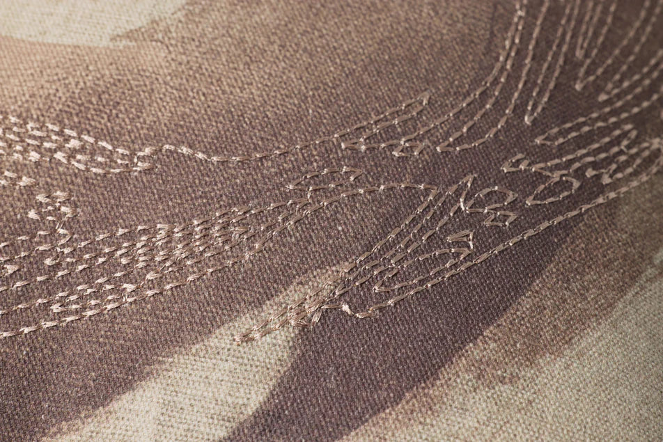 Close-up of embroidered fabric with intricate patterns on a brown background