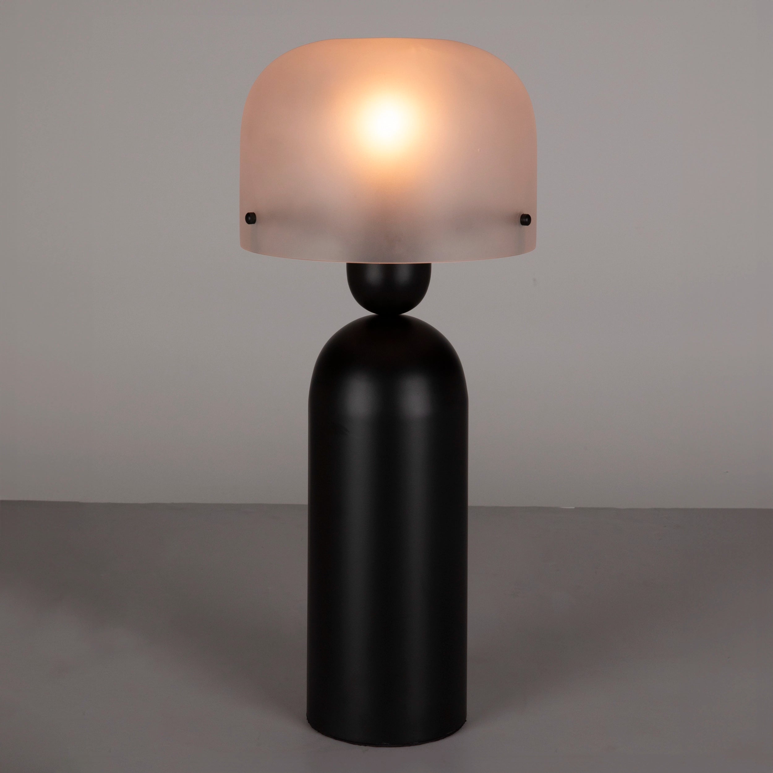 Table lamp with a black base and frosted glass shade on a gray background