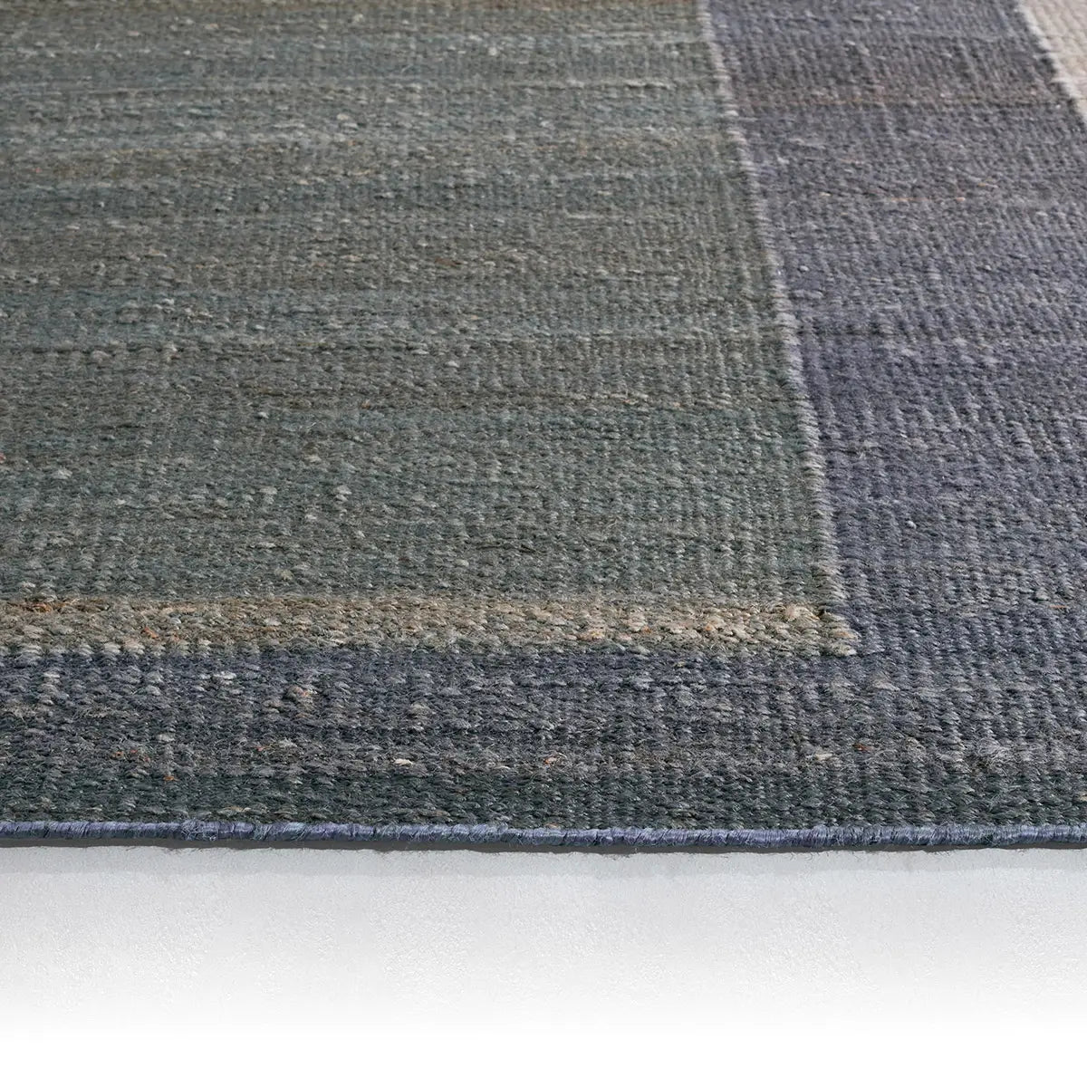 Close-up of a textured blue and gray rug on a white surface