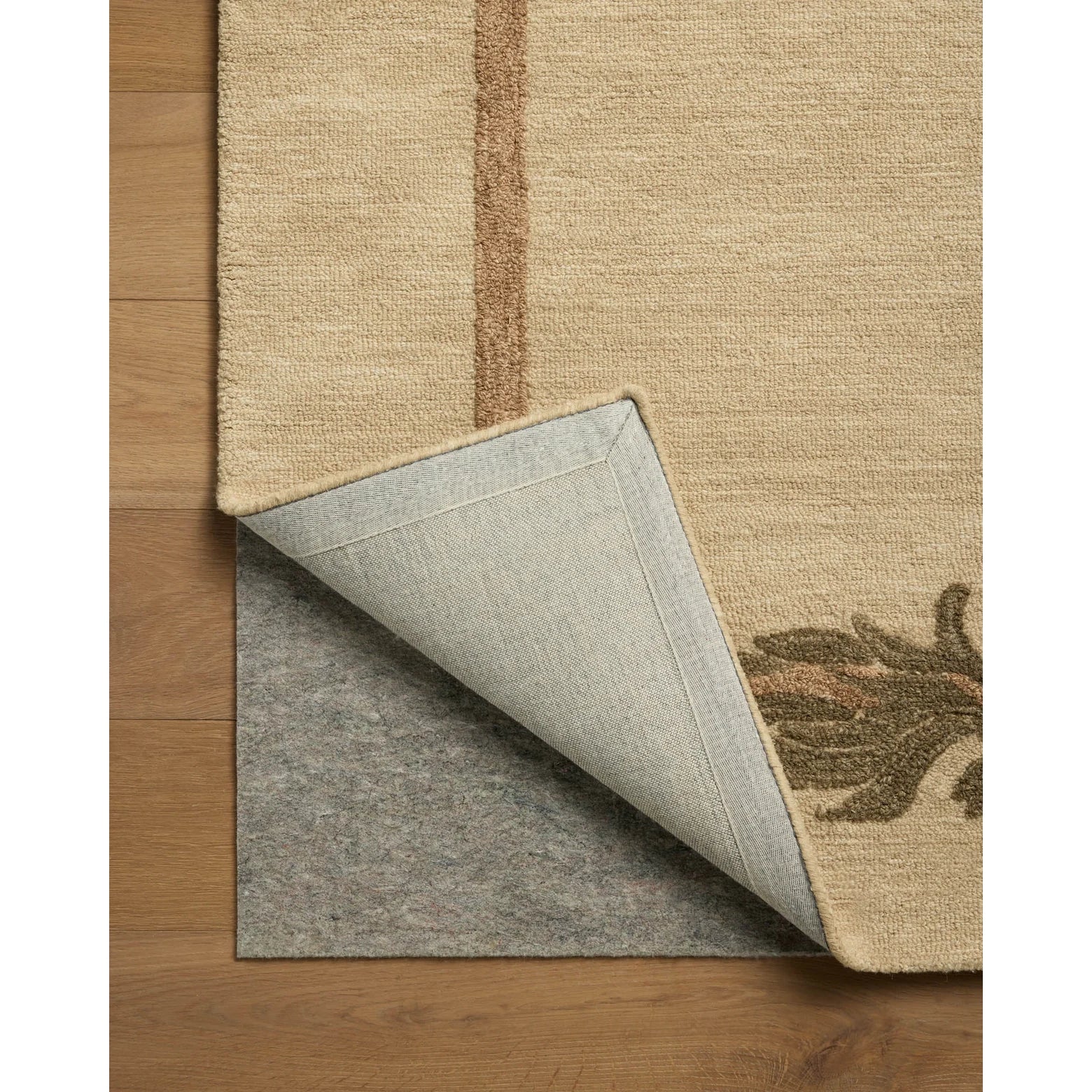 Close-up of a beige rug with a textured border on a wooden floor.