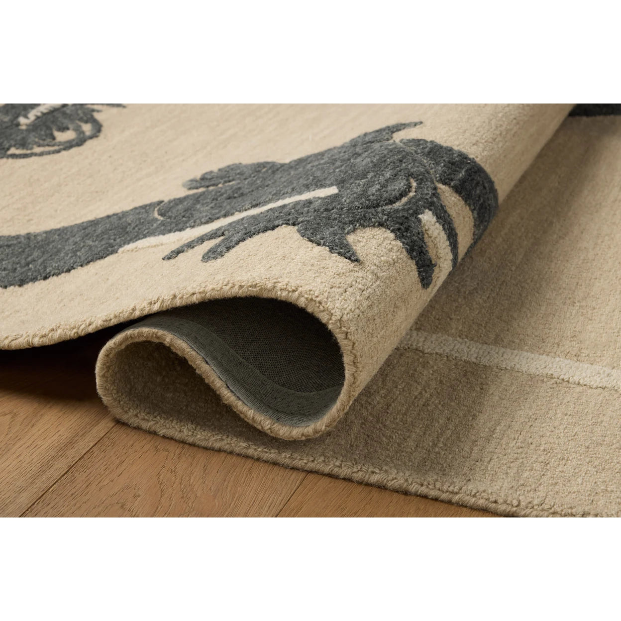 Close-up of a beige rug with a dark pattern on a wooden floor