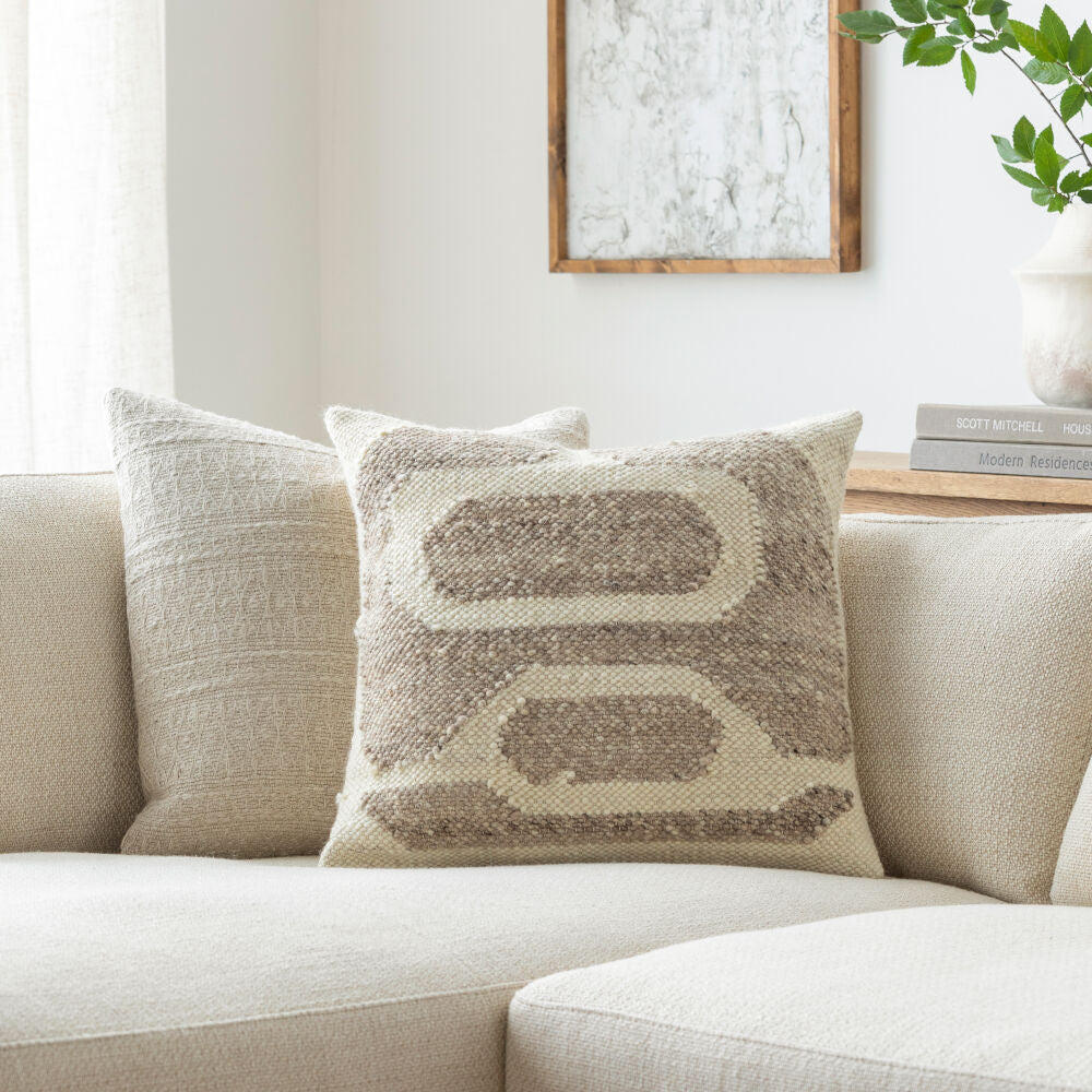 Decorative pillow on a beige sofa with a neutral color scheme
