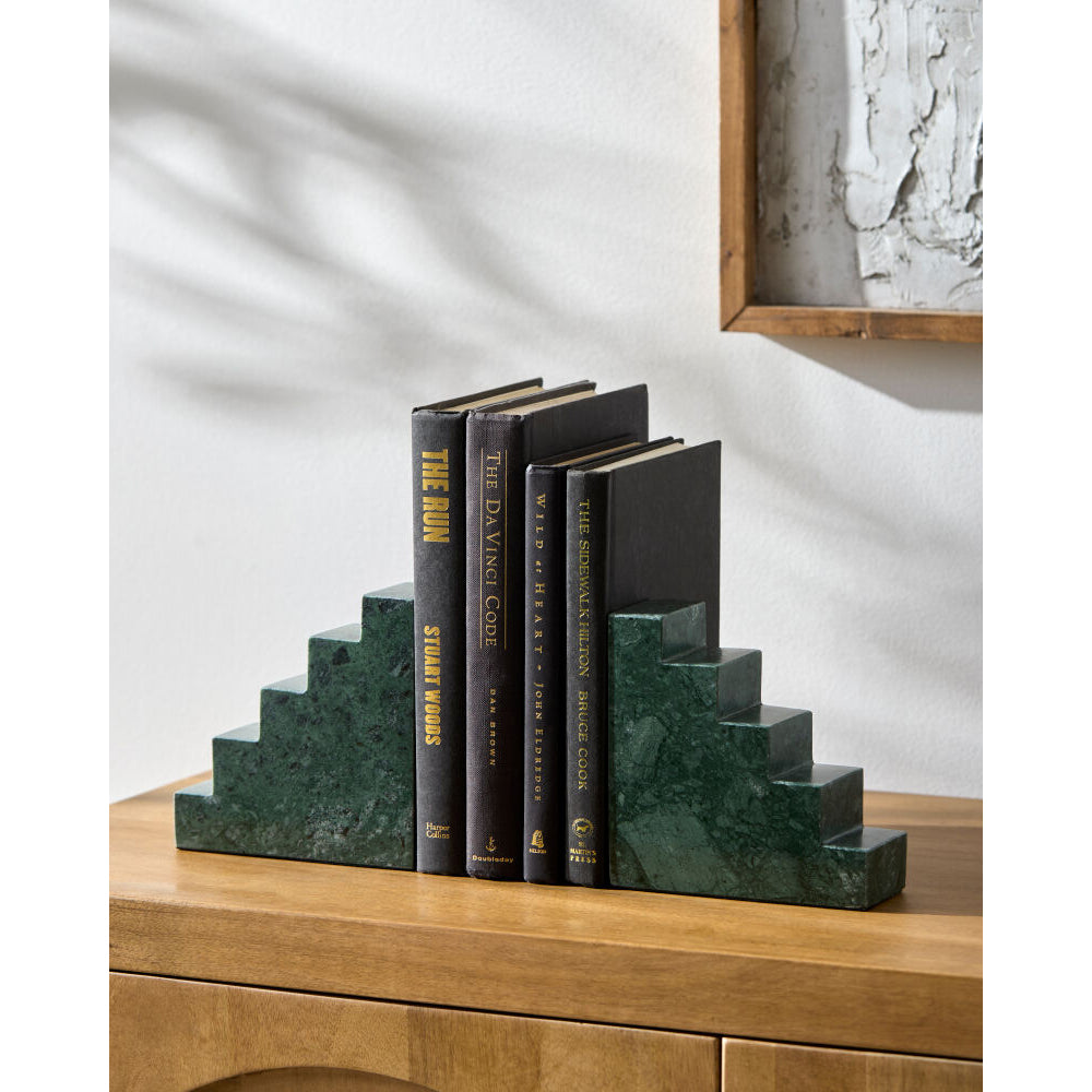 Marble bookends with books on a wooden surface against a white wall.