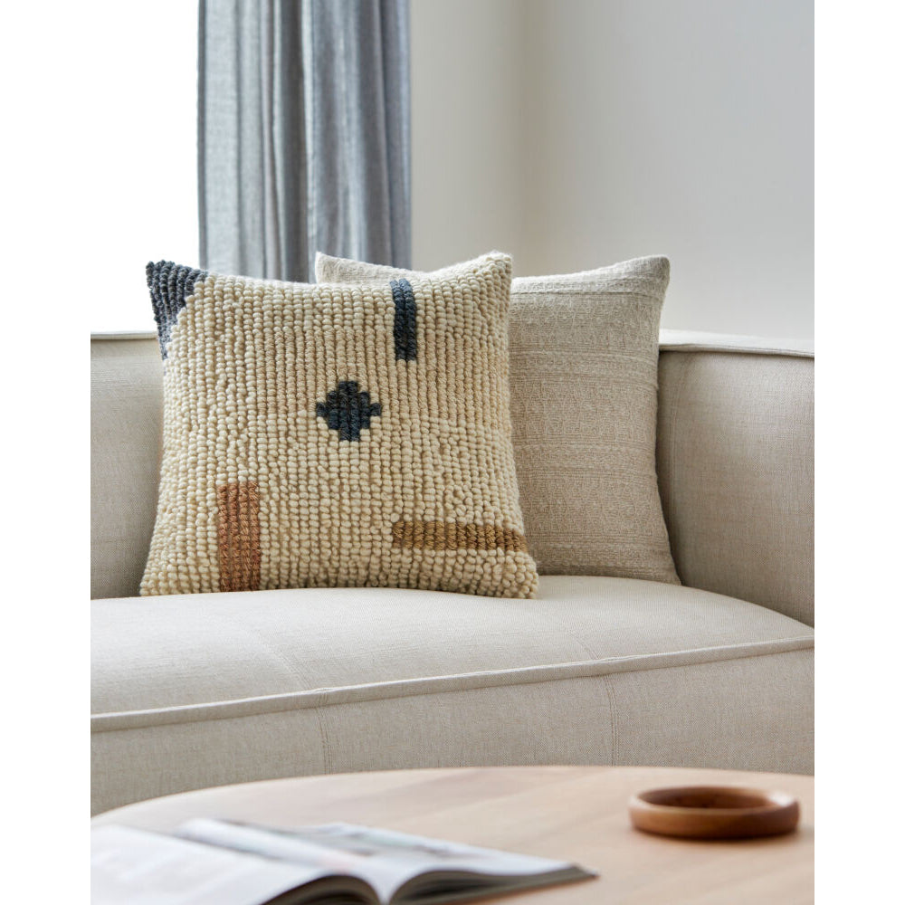 Decorative pillows on a beige sofa with a neutral background