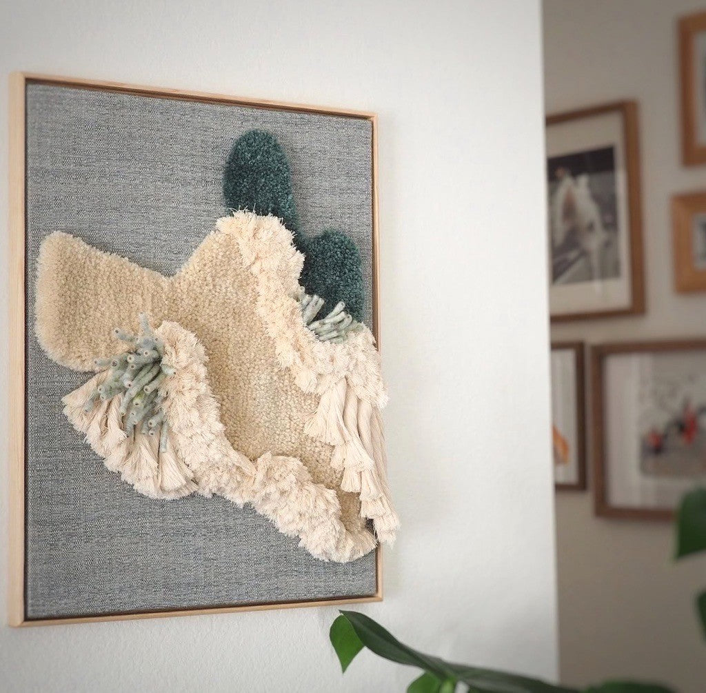 Textured wall art with floral design on a gray background, framed in a wooden border.