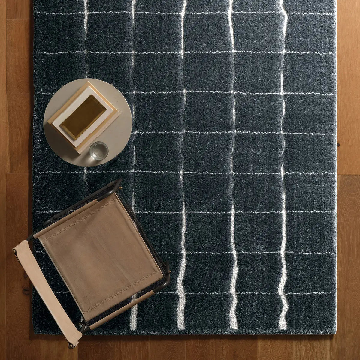 Dark gray rug with white grid pattern on a wooden floor