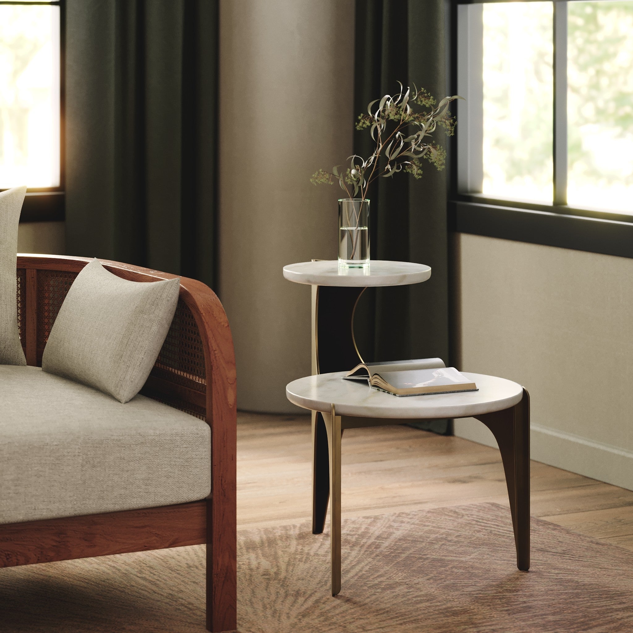A modern two-tier side table with white marble-look round tops and curved gold metal legs, styled in a warm, contemporary living room next to a wooden armchair.