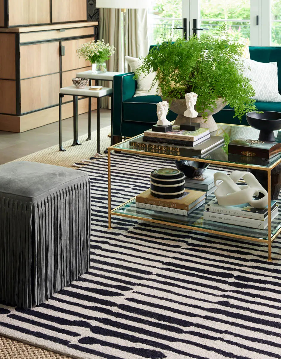 Modern living room with striped rug, glass coffee table, and decorative items.