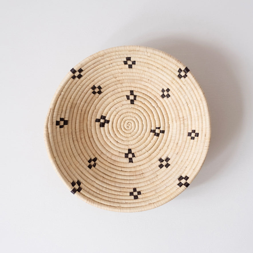 Woven basket with black patterns on a light gray background