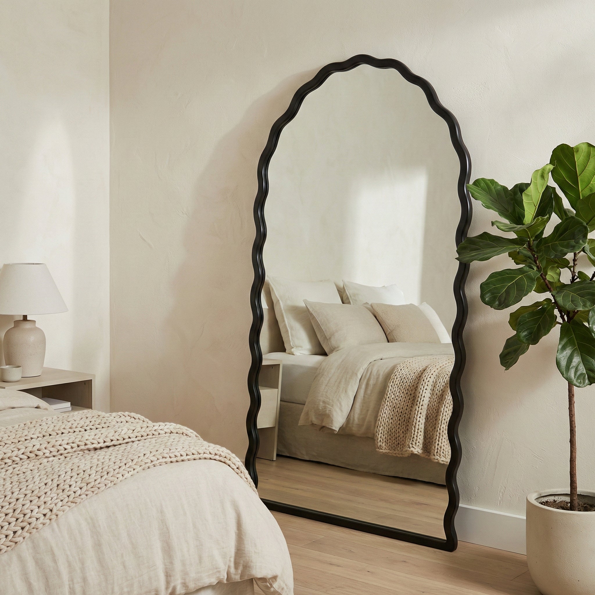 Large decorative mirror in a bedroom setting with a bed and plant.