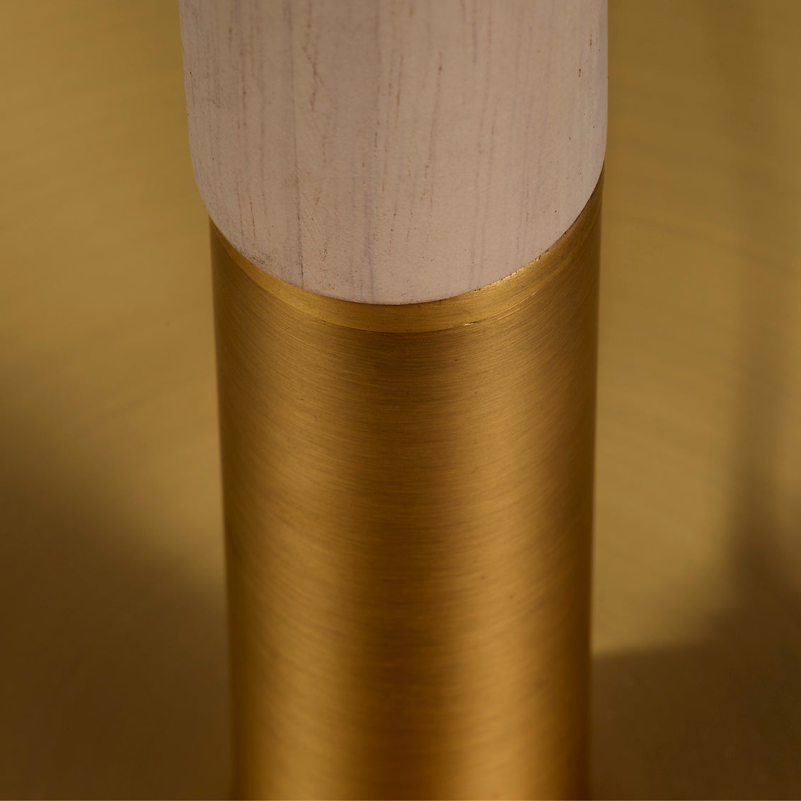 Close-up of floor lamp with a wooden and brass base on a gold background