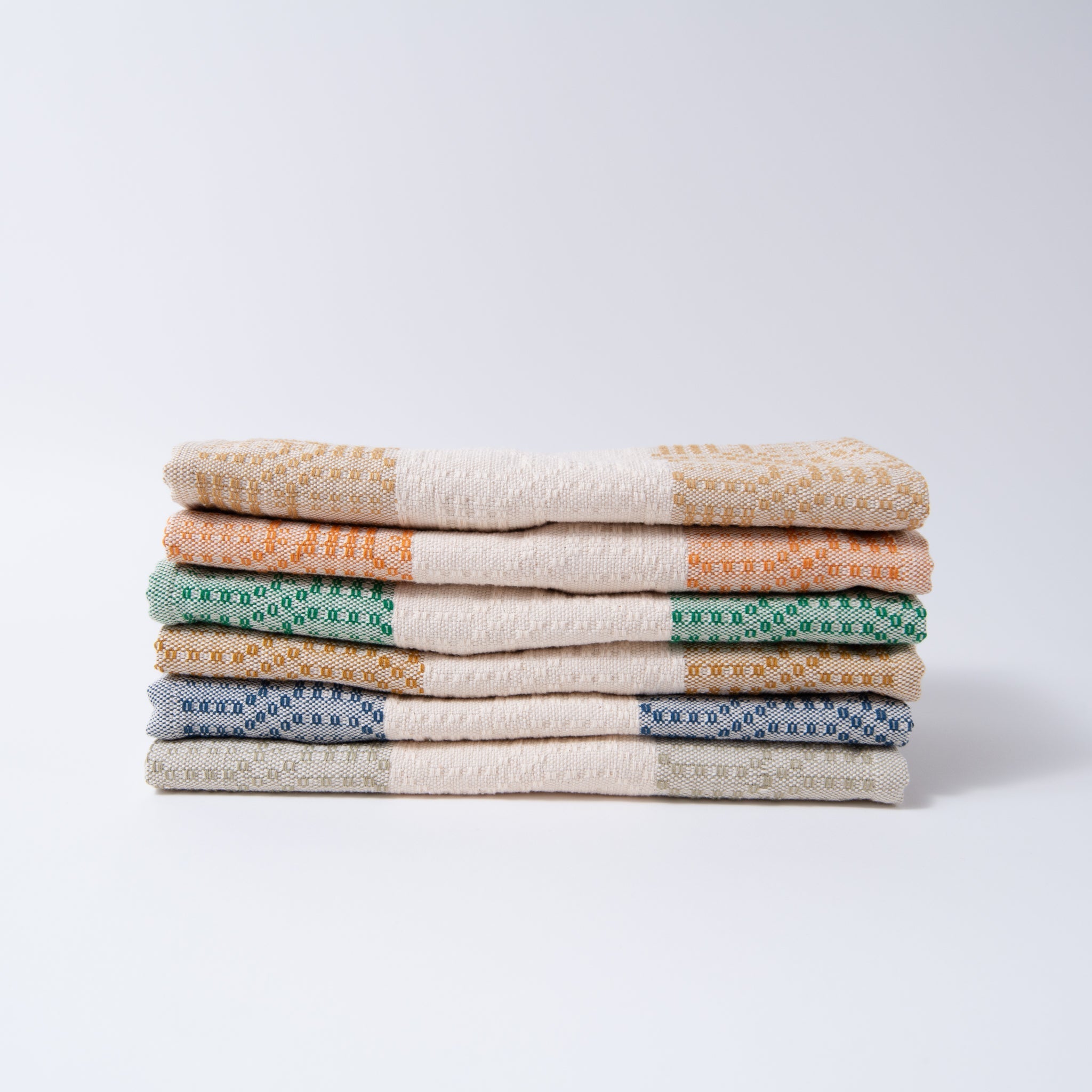 Stack of folded towels in various colors on a white background