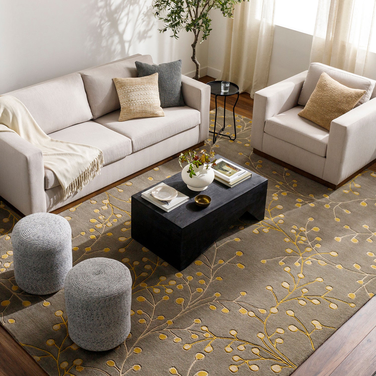 Living room with beige sofa, ottomans, and a coffee table on a patterned rug.