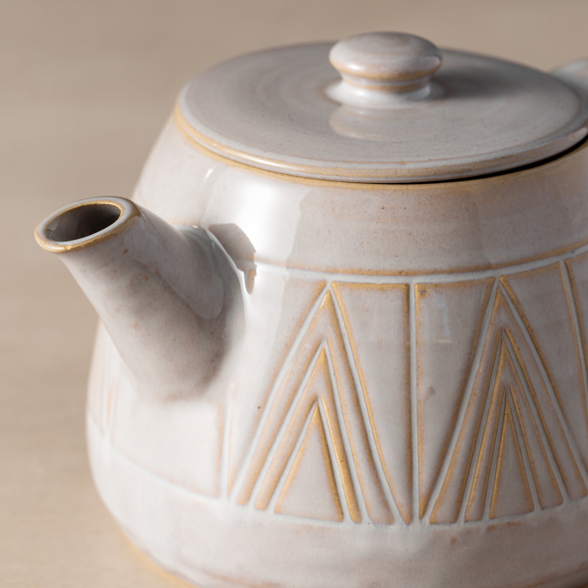 Ceramic teapot with geometric patterns on a beige background