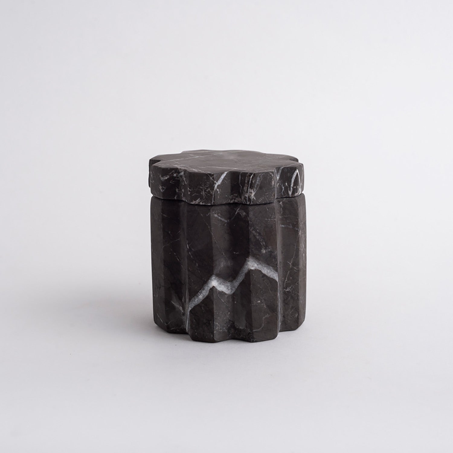 Black marble container with a lid on a white background