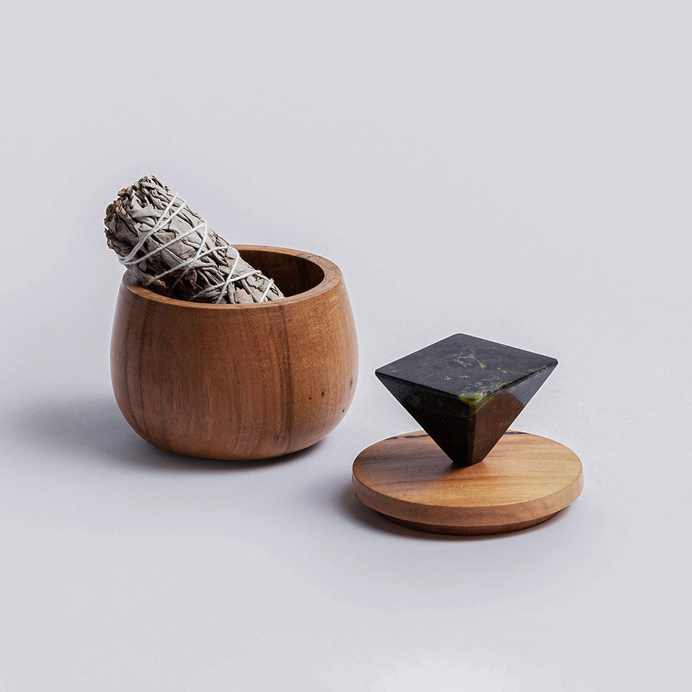 Wooden box with smudge stick and black geometric handle on a light gray background