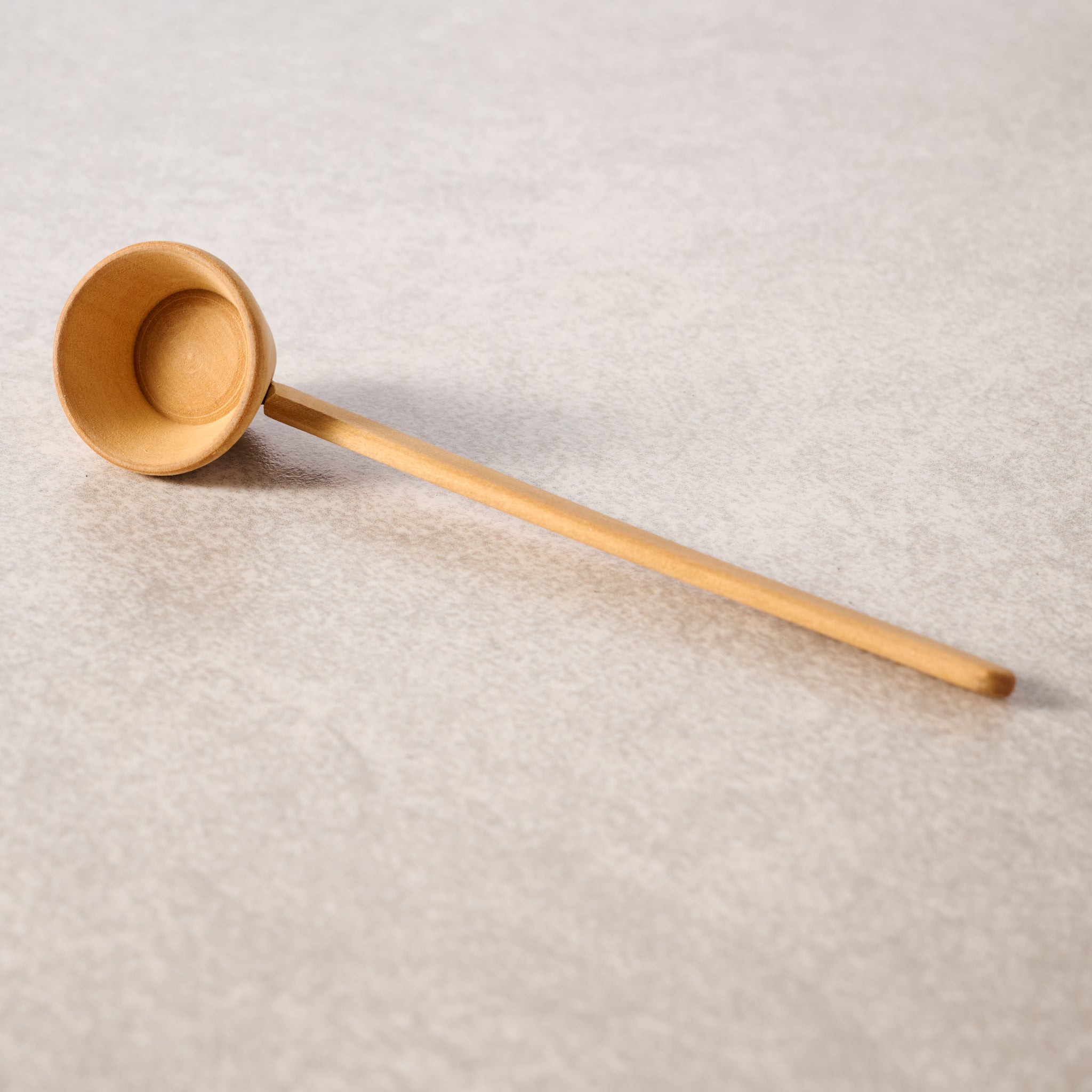 Wooden ladle on a textured beige surface