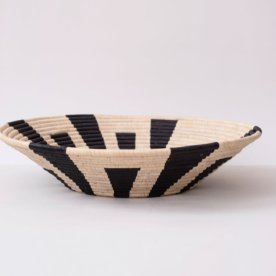 Woven bowl with black and beige pattern on a white background