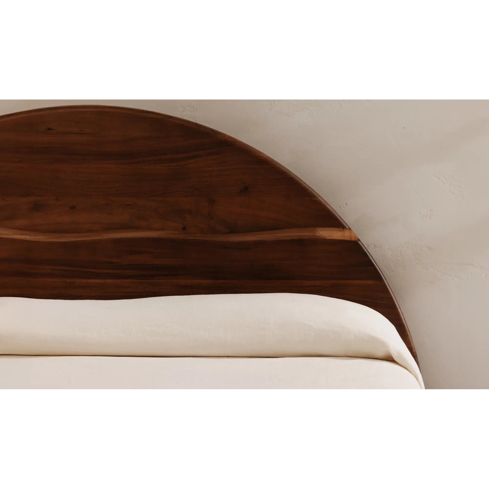 Wooden headboard with white bedding against a neutral wall