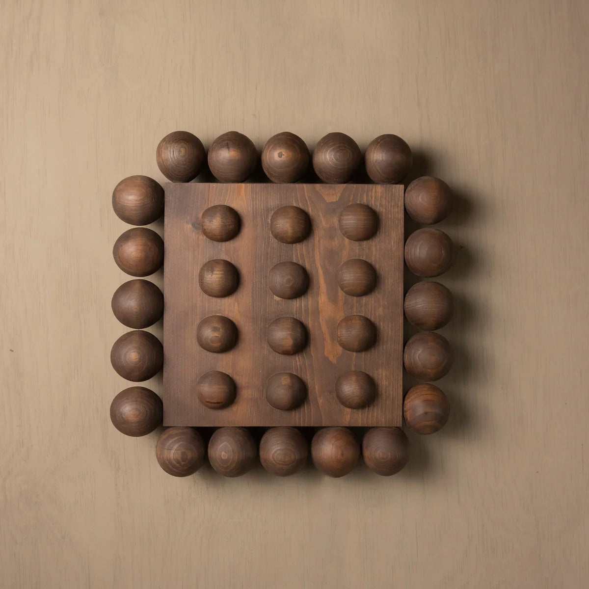 Wooden wall art with spherical protrusions on a beige background
