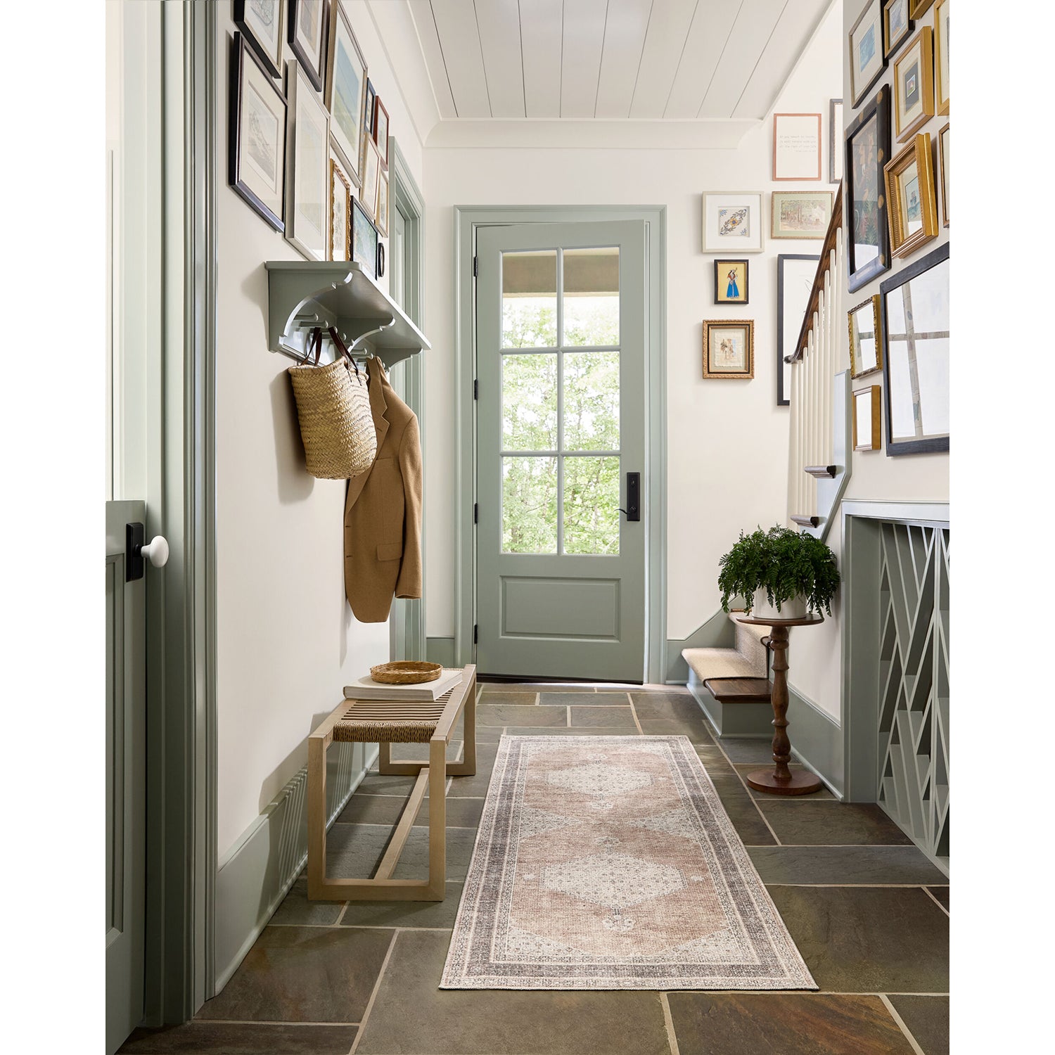 Entryway with a green door, coat rack, and framed pictures on the wall.