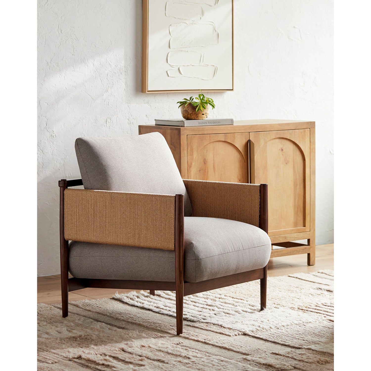 Chair with wooden frame and gray cushion in a room with a wooden cabinet and plant.