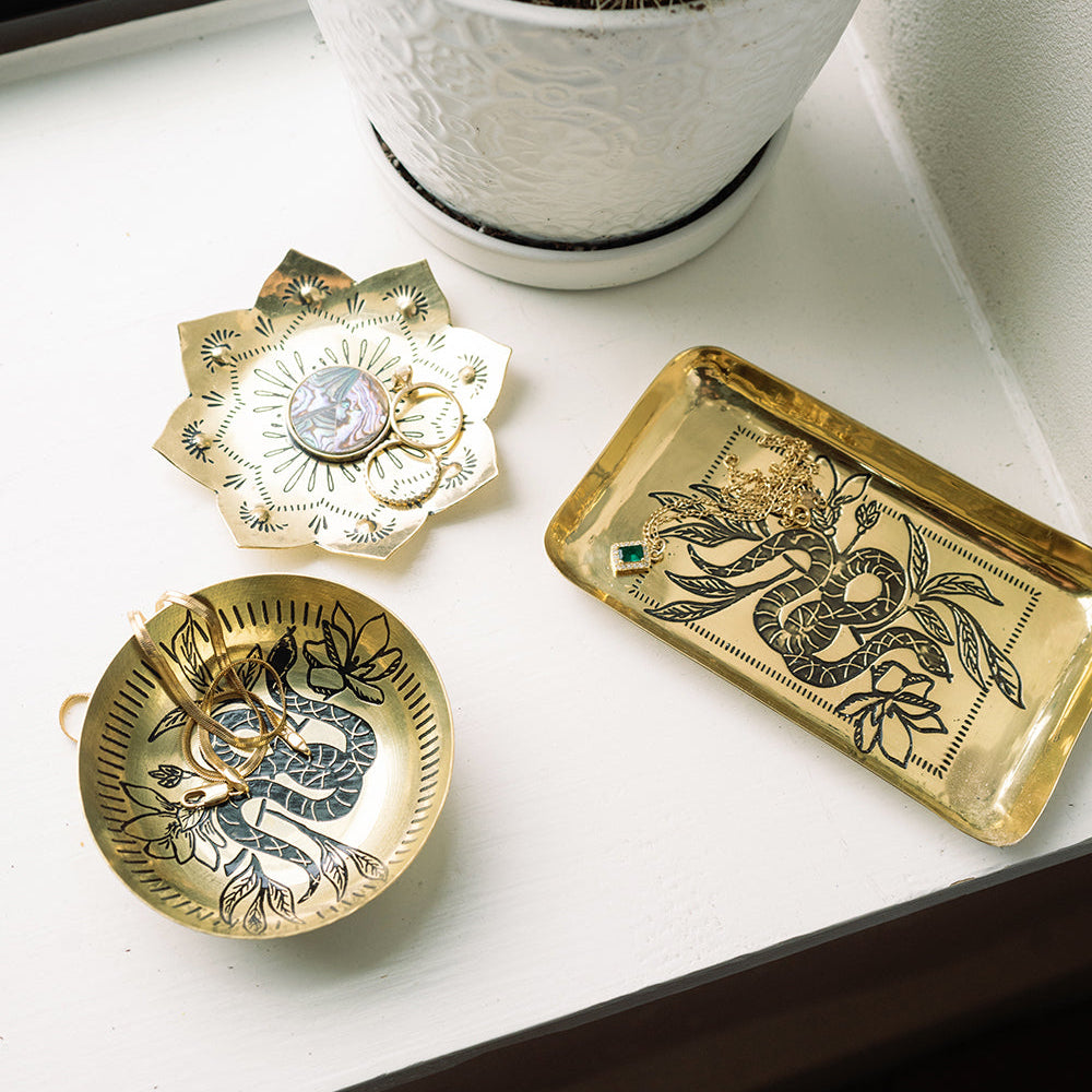 Three decorative metal trinket dishes with intricate designs on a white surface.