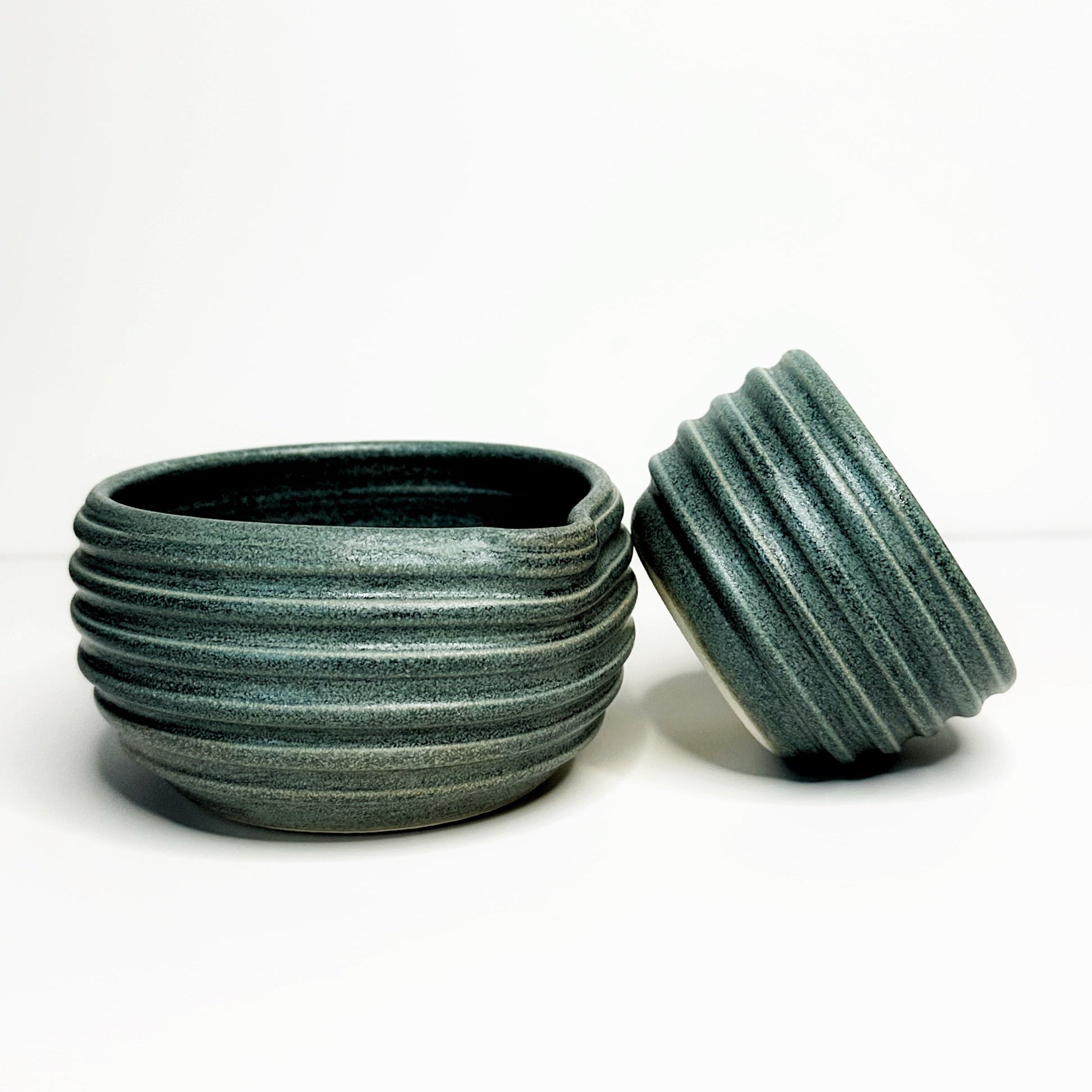 Two green ceramic bowls with textured surfaces on a white background