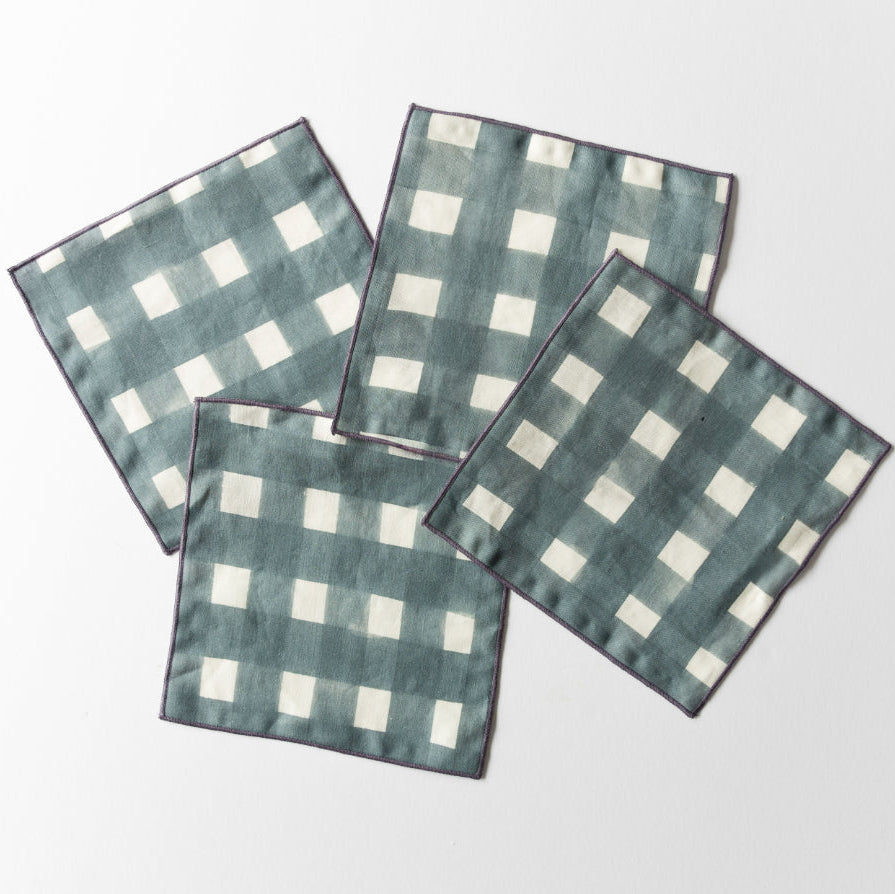 Four blue linen plaid napkins on a white background